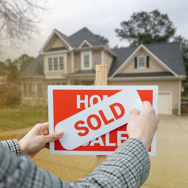 Real estate agent placing a sold sign over a for sale sign in front of a home after a successful property sale.  If you'd like, I can localize them slightly for Alaska search relevance without keyword stuffing.