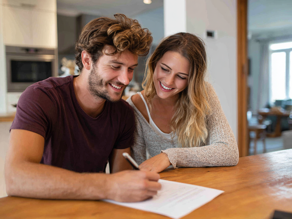 young couple signing home sale docs