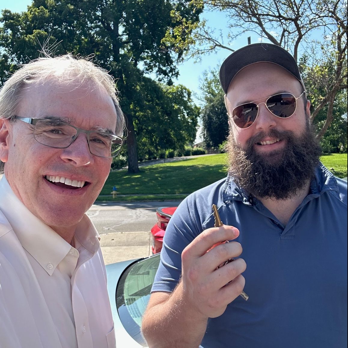 David Campbell realtor stands next to Jake as they both face towards the camera, smiling. Jake is holding house keys.