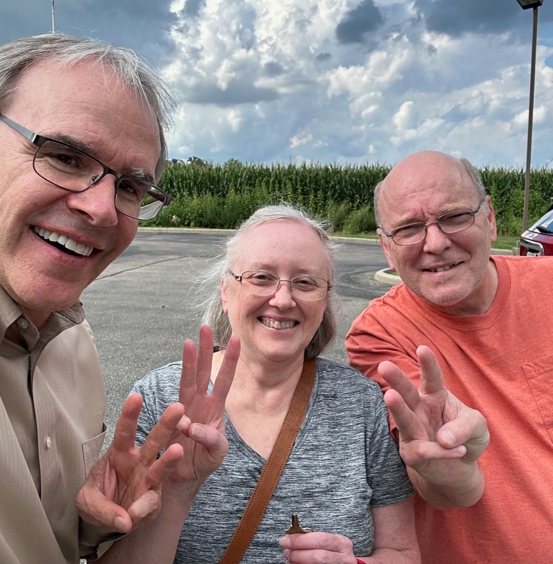 David Campbell realtor stands next to both Nancy and Jack. All three of them are facing the camera, smiling and holding up three fingers. Nancy is holding a house key.
