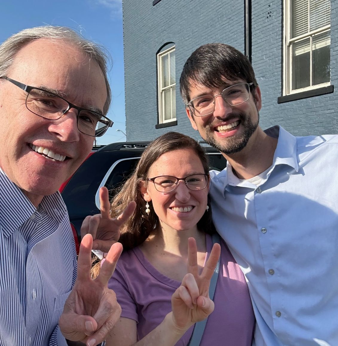 David Campbell realtor stands next to both Chase and Hannah. They're all holding up two fingers while facing towards the camera, smiling.