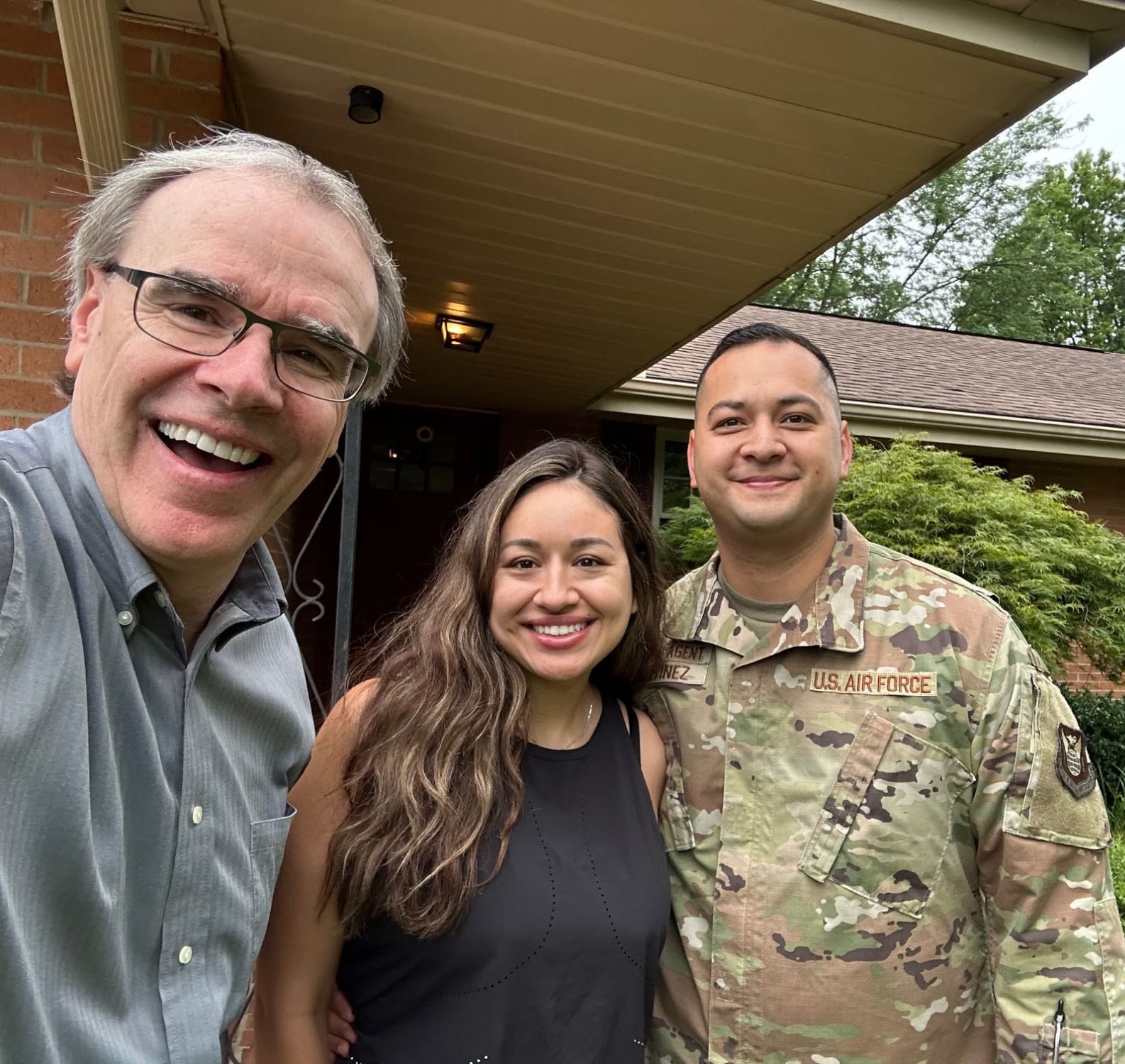 David Campbell, realtor, stands next to both Carlos and Claudia as they all face towards the camera, smiling.