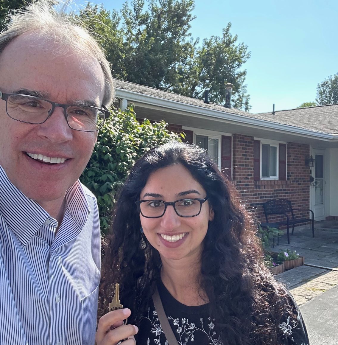 David Campbell realtor stands next to Hanen as they both face towards the camera, smiling. Hanen is holding up a house key.