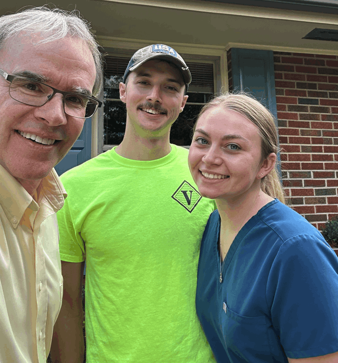 David Campbell realtor stands next to Hanen as they both face towards the camera, smiling. Hanen is holding up a house key.