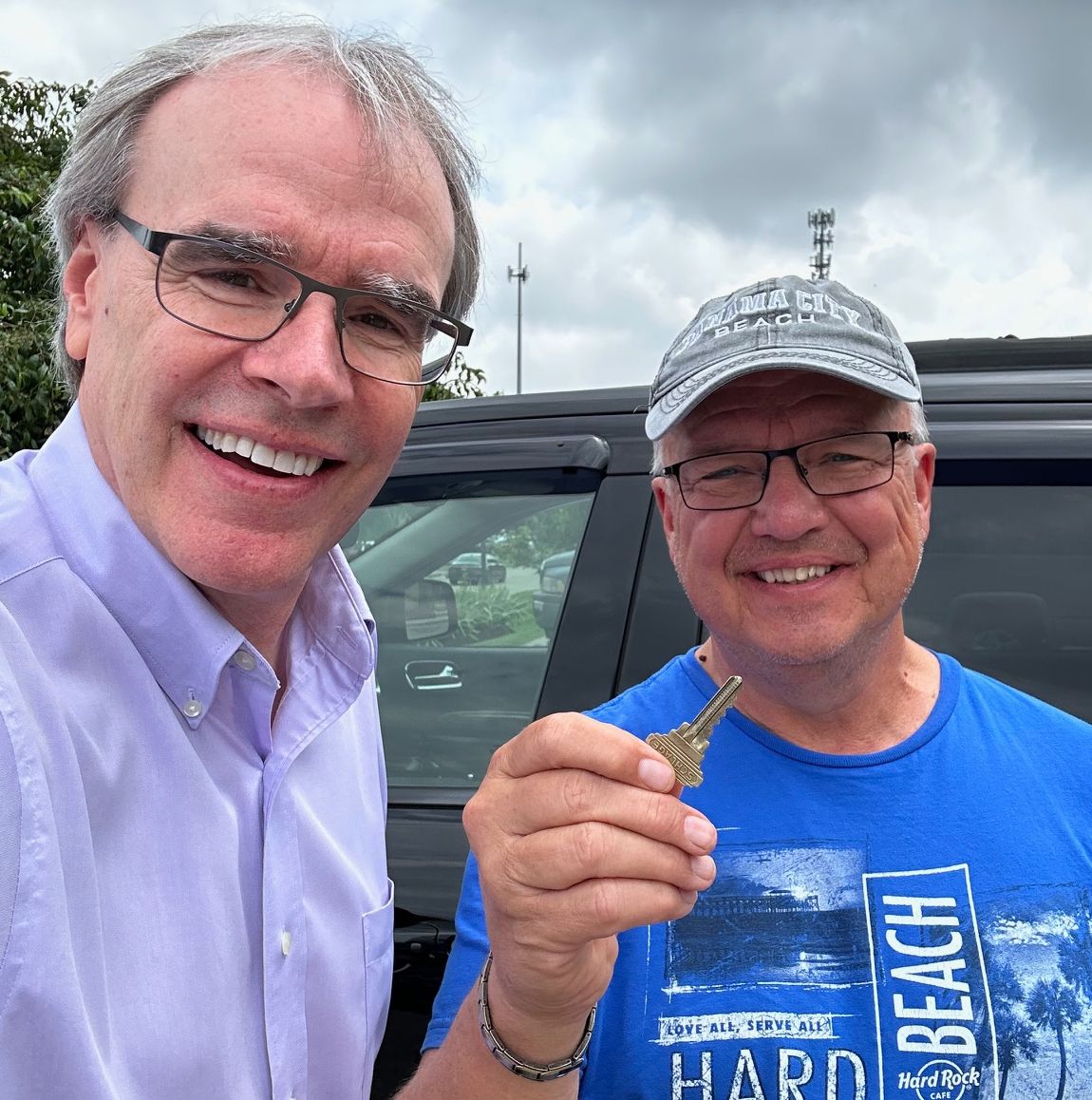 David Campbell, Realtor stands next to a man holding a house key - they're both smiling towards the camera after a condo purchase. 