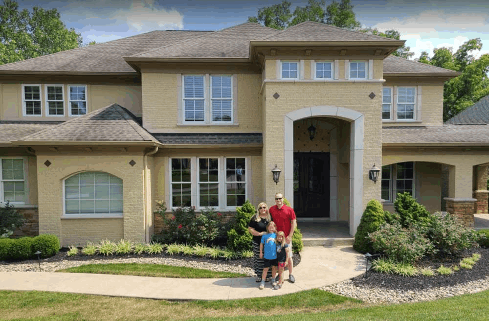 Paul and Michele stand with their children in front of a large home in Lebanon, OH.