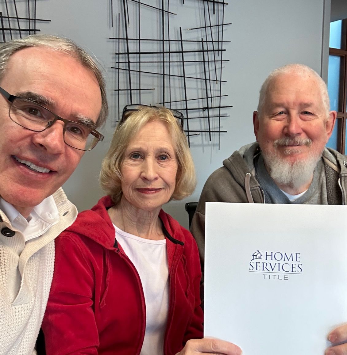 David Campbell, realtor sits next to Ken and Cindy as they all face towards the camera smiling after a successful home sale.