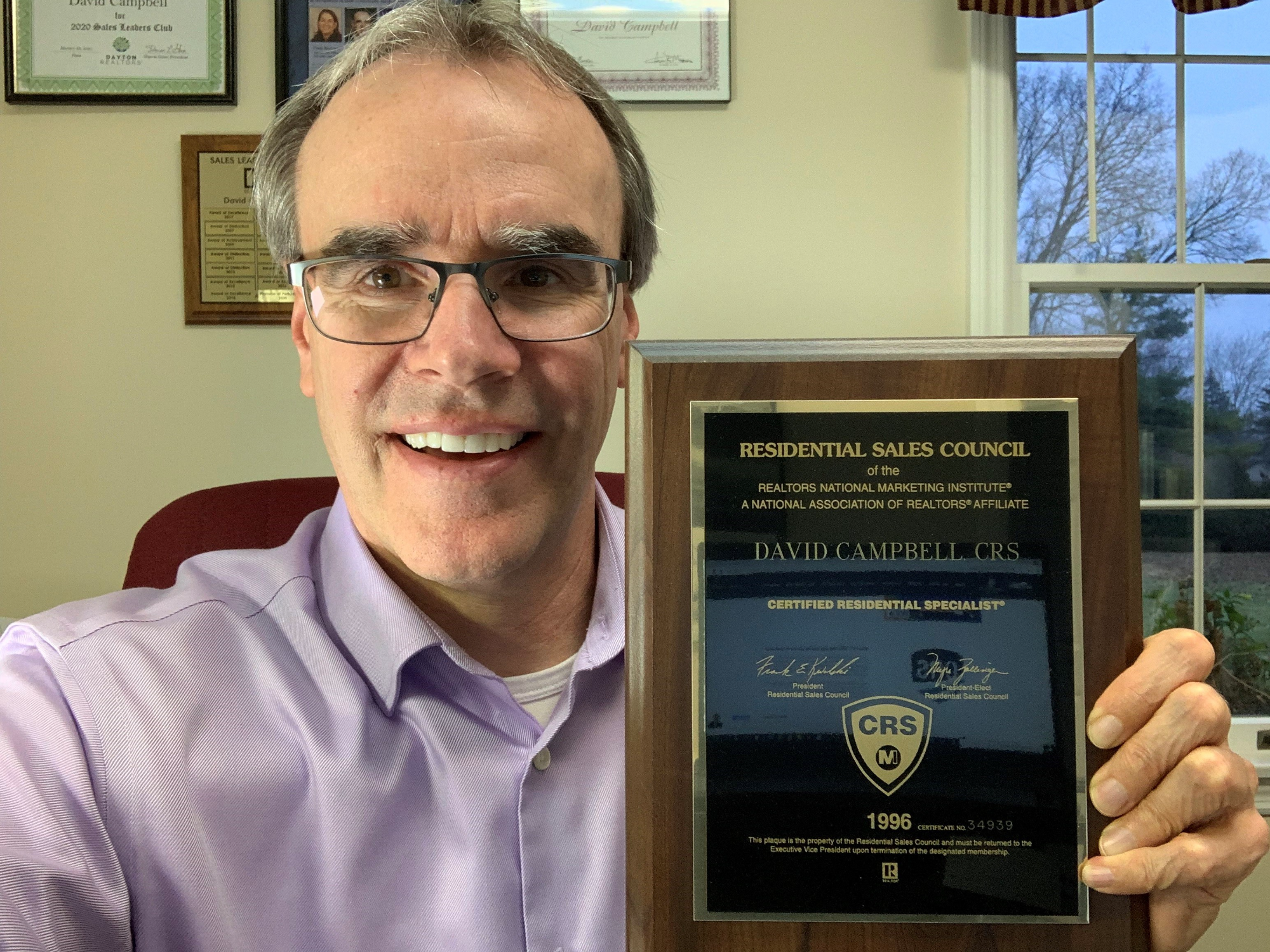 David Campbell realtor, holds up a plaque shows he's an official Certified Residential Specialist (CRS).