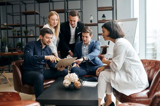 Stock Image of people in suits deliberating over a clipboard.