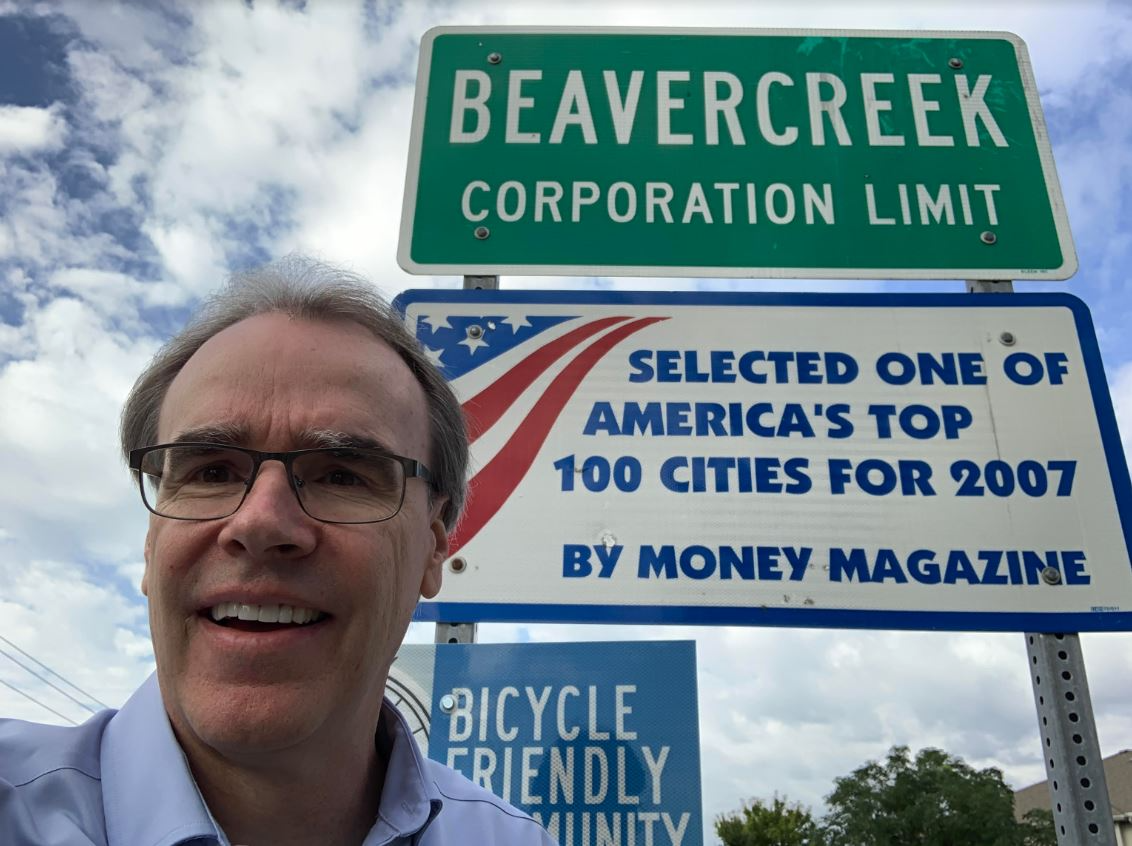 David Campbell realtor, stands in front of a sign that reads "Beavercreek Corporation Limit."