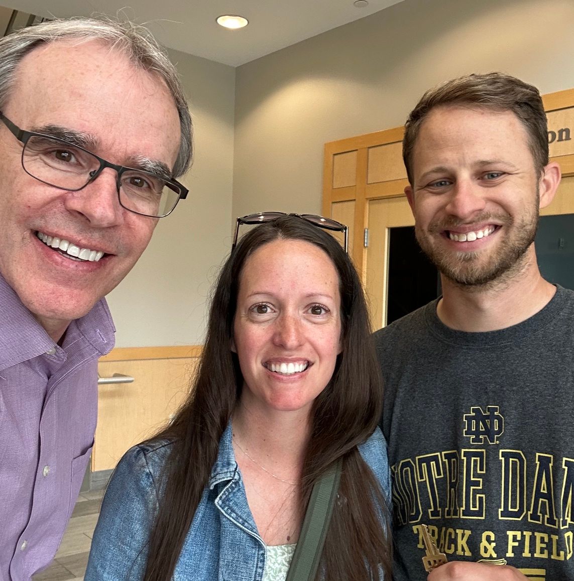David Campbell, local Dayton realtor, stands next to both Tim and Hali. Tim is holding a house key as they all face the camera, smiling.