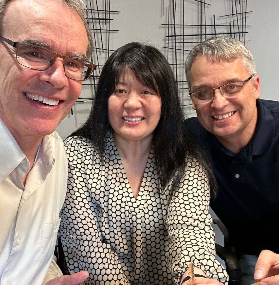 Rob and Theresa sit next to David Campbell, realtor, all smiling and facing toward the viewer. Theresa is holding a house key.