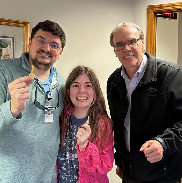 David Campbell stands to the right of a man and women who are both holding up keys. They are all smiling towards the camera.