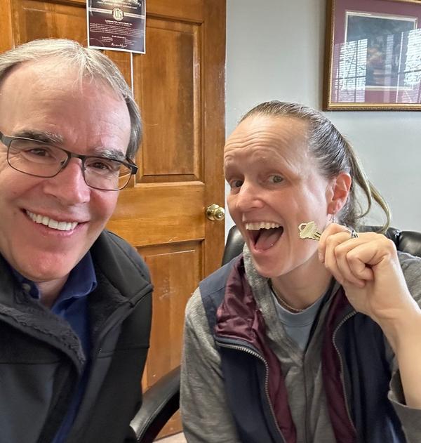 David Campbell sits next to a women who's holding a house key. They are both smiling towards the camera.