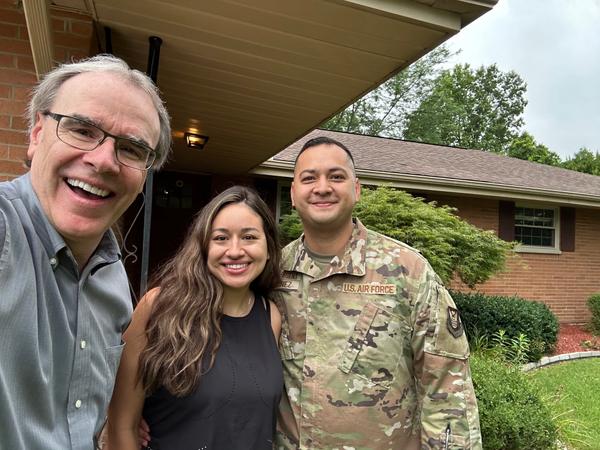 David Campbell, realtor, stands next to a man and woman - Carlos and Claudia - as they all look towards the camera, smiling.