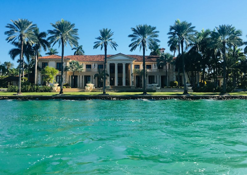 Large waterfront estate with a tile roof and royal palms