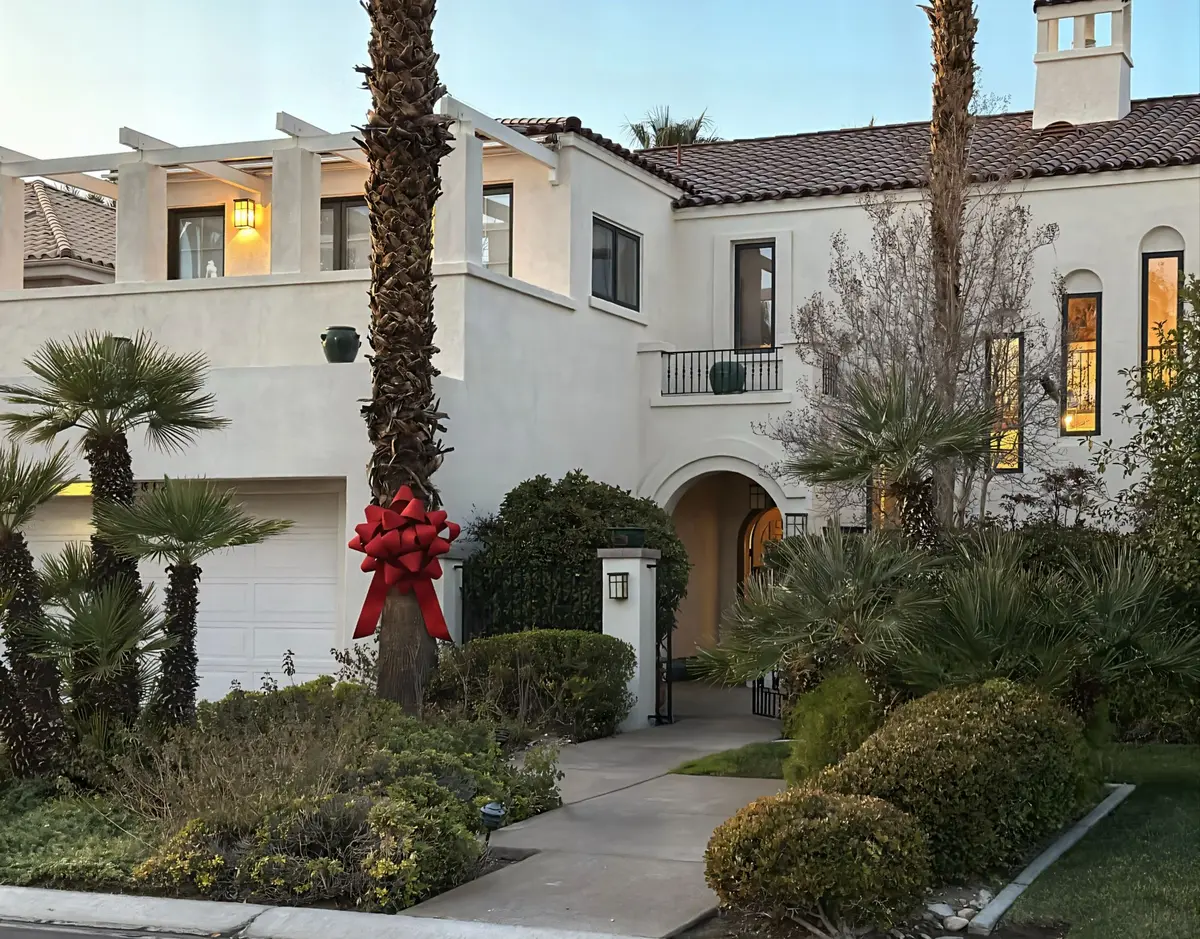 Front exterior of a $2.4M luxury home in Canyon Gate, Las Vegas — sold by Las Vegas Real Estate Broker-Salesperson Ina Medina. A signature five-foot celebration bow is tied around the palm tree, representing the Ina Medina Experience and her award-winning, client-focused approach. Featured in the About page's recognition section.