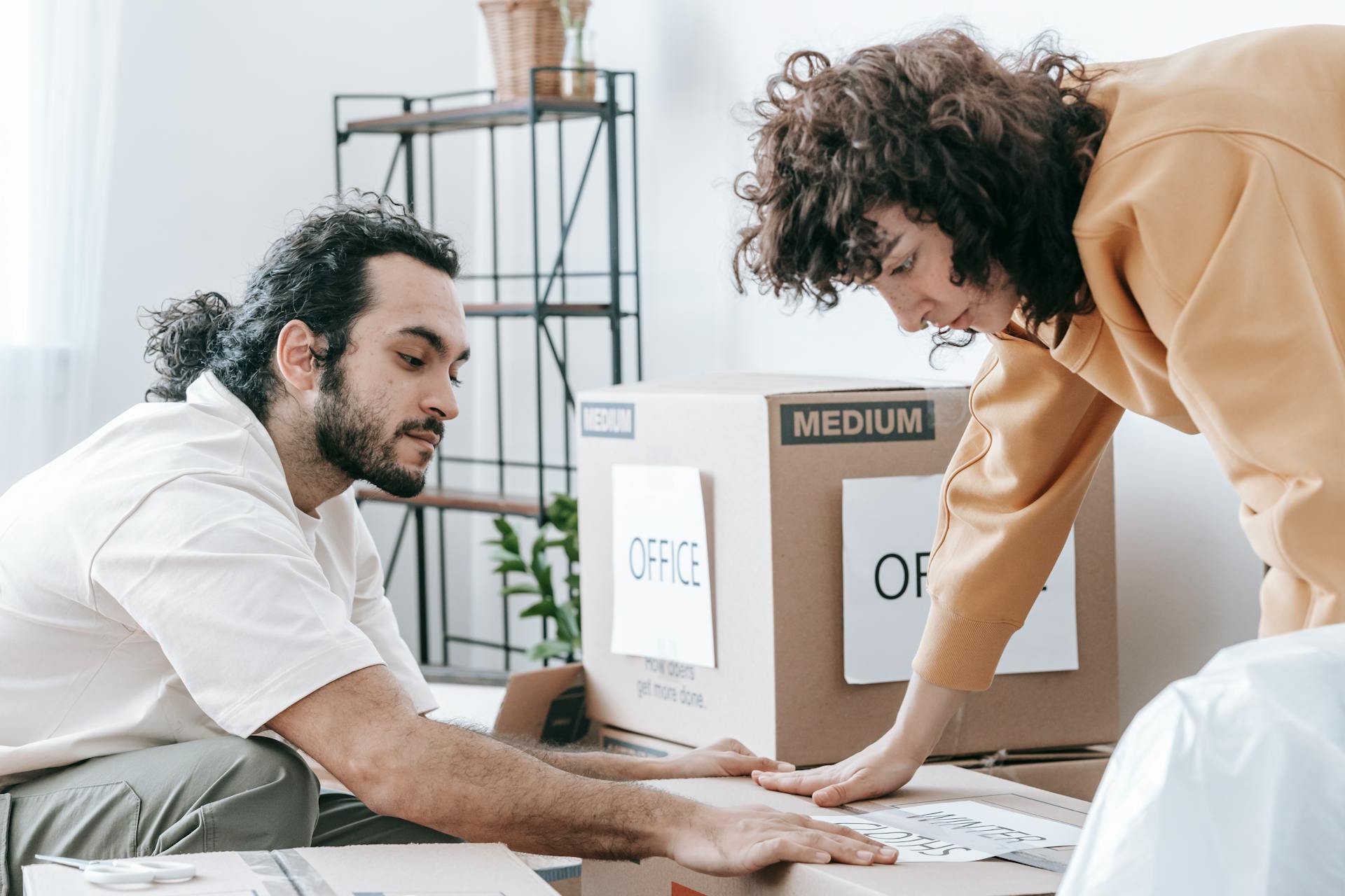 Couple packing boxes in a tidy home.