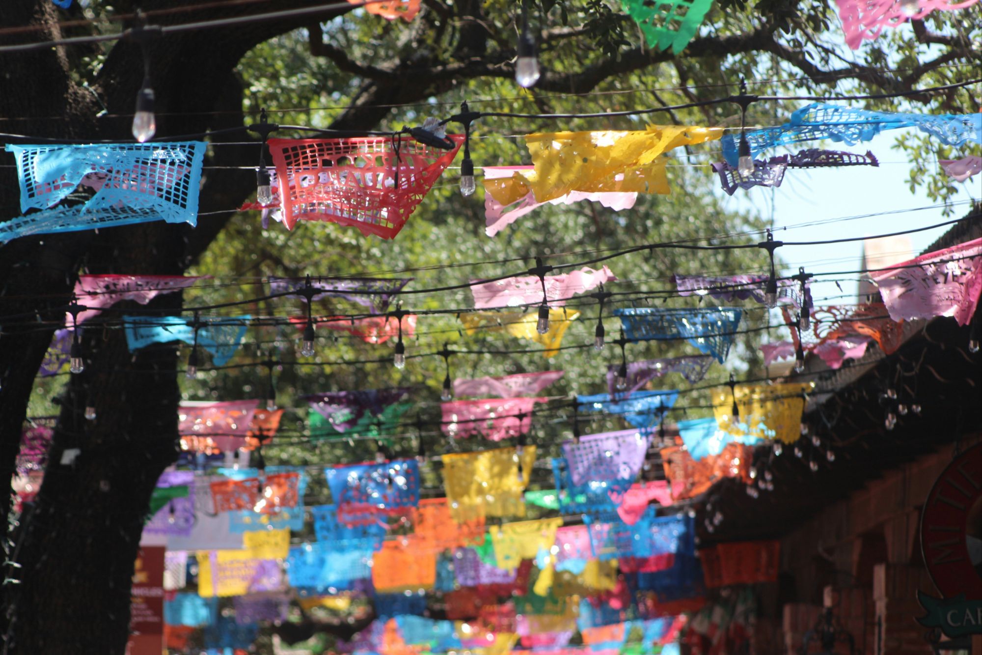 Colorful papel picado banners strung across Market Square in San Antonio on a sunny day