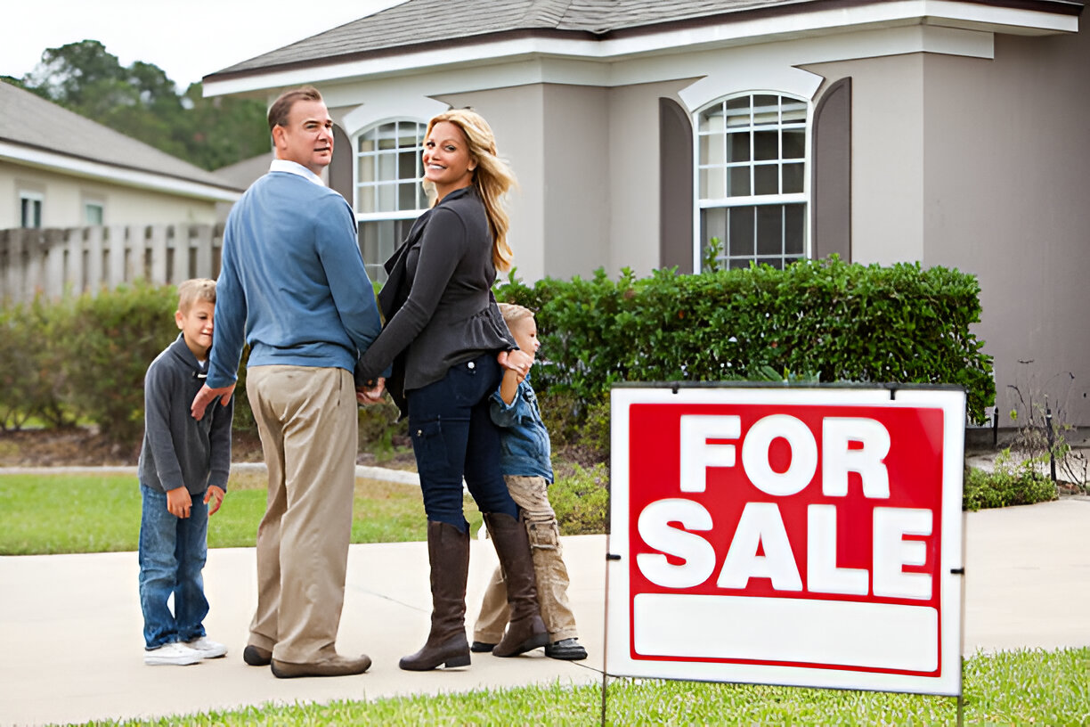 Family in front of a San Antonio home with a For Sale sign