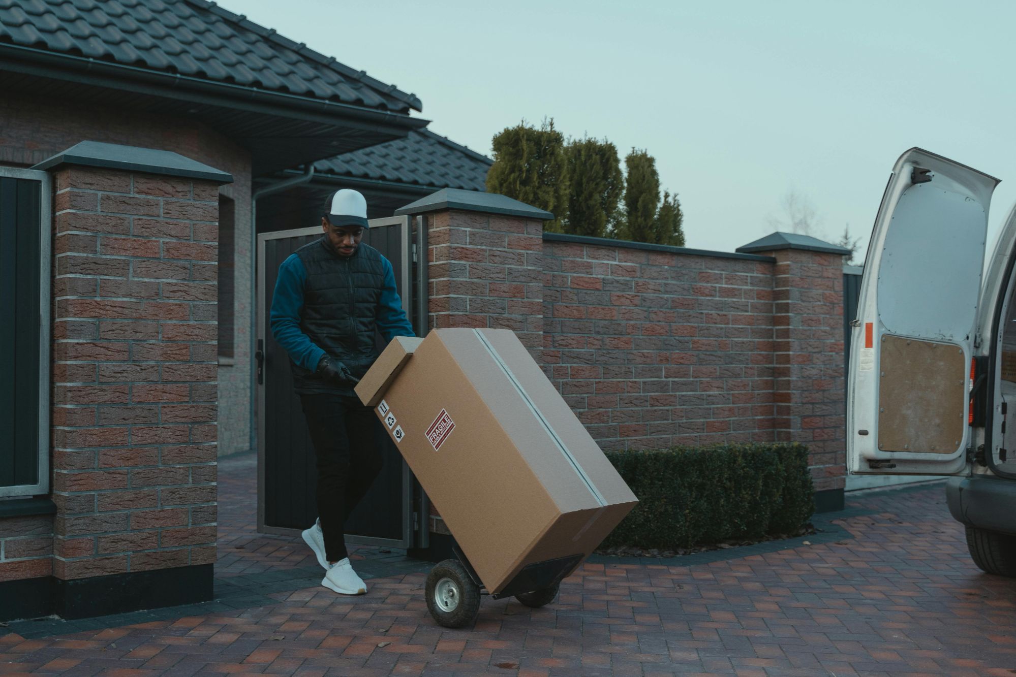 A person moving a large box from a vehicle to a home, symbolizing the packing and moving process during a relocation.
