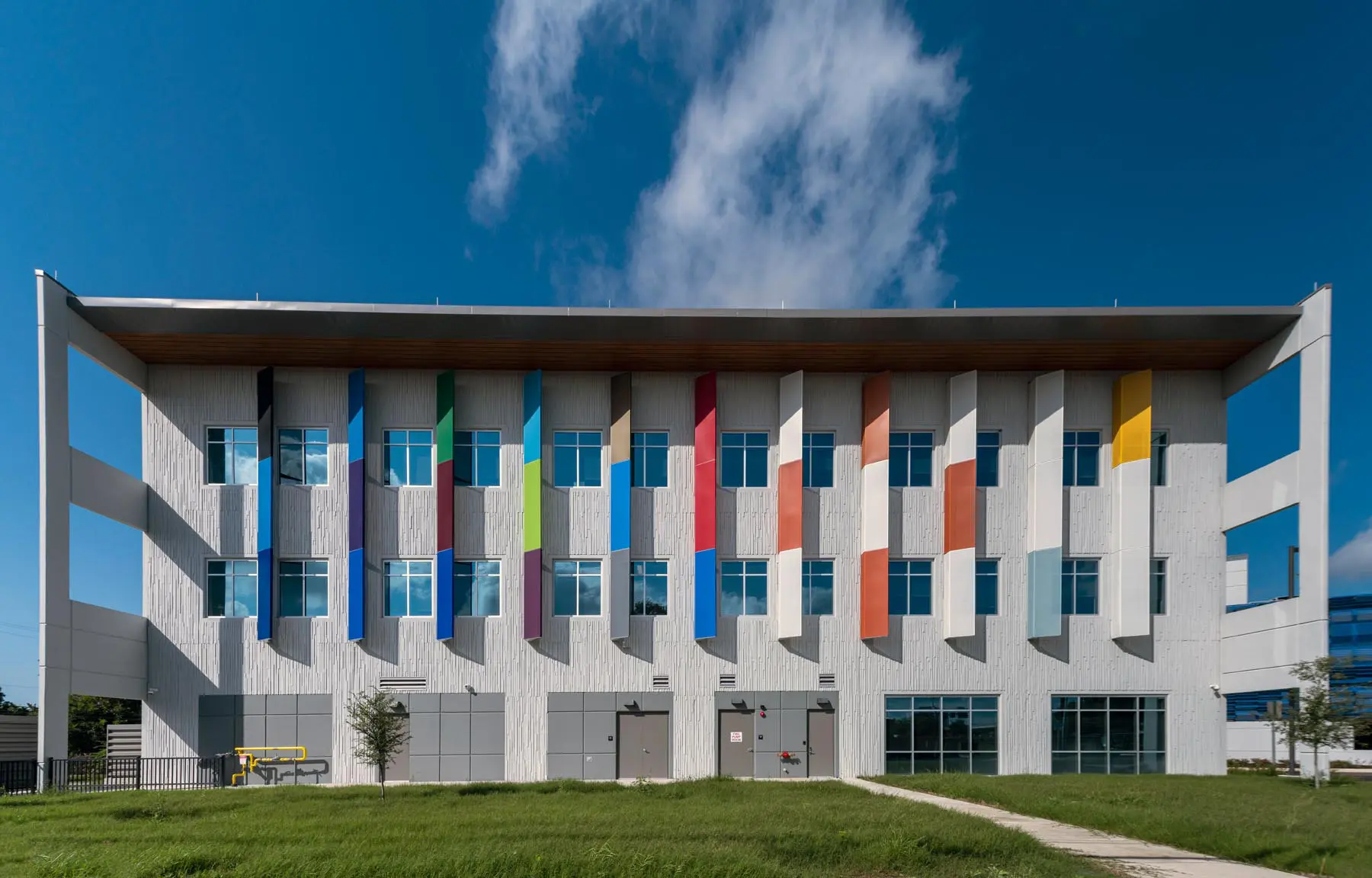 Exterior of the San Antonio Independent School District Central Office Administration Building, featuring colorful vertical panels on the facade against a clear blue sky.
