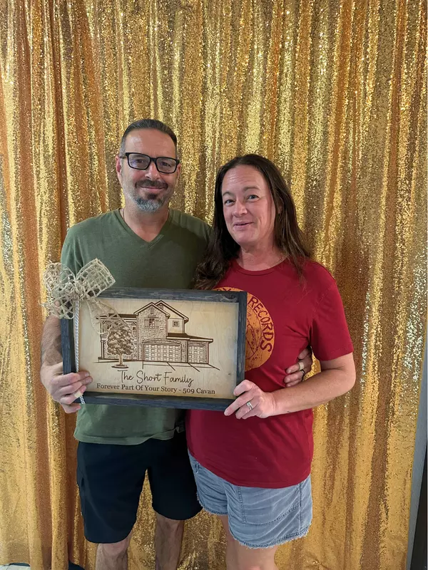 Celebrating closing day at Succession Title, with client holding a jar of home-related items and posing with Anthony Sharp