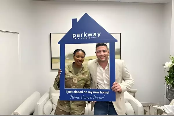 Anthony Sharp and an Air Force member frame themselves in a Parkway Title cut-out that reads ‘I just closed on my new home, Home Sweet Home.