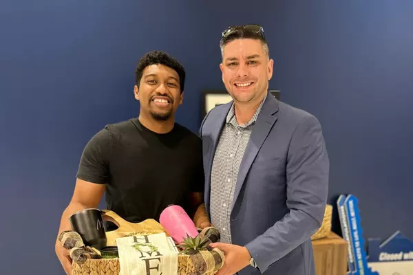 Military service member and Realtor Anthony Sharp holding a welcome-home gift basket after closing on a new home near JBSA Randolph Air Force Base in San Antonio, Texas