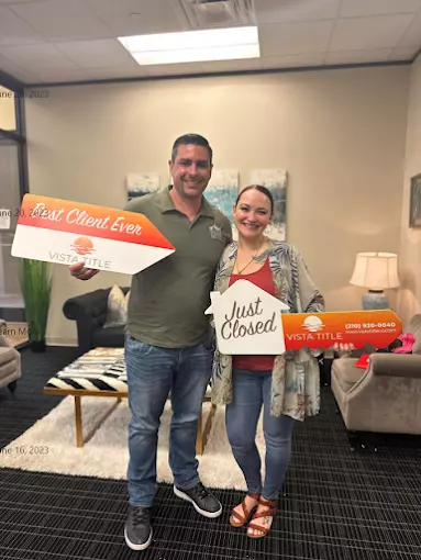 Buyer and Anthony Sharp celebrate at Vista Title, holding ‘Best Client Ever’ and ‘Just Closed’ signs