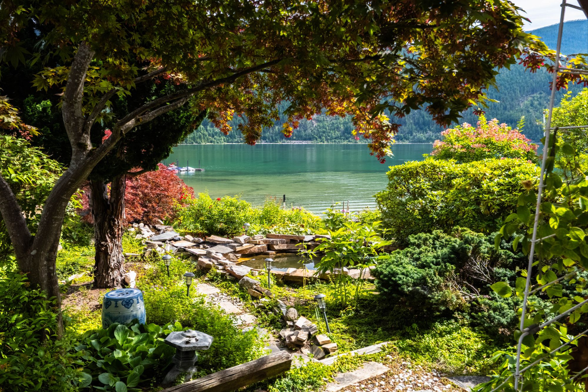 Beautiful landscaped garden with koi pond and lush greenery overlooking Kootenay Lake at 1896 Hwy 3A, Nelson BC waterfront home MLS® 10360967