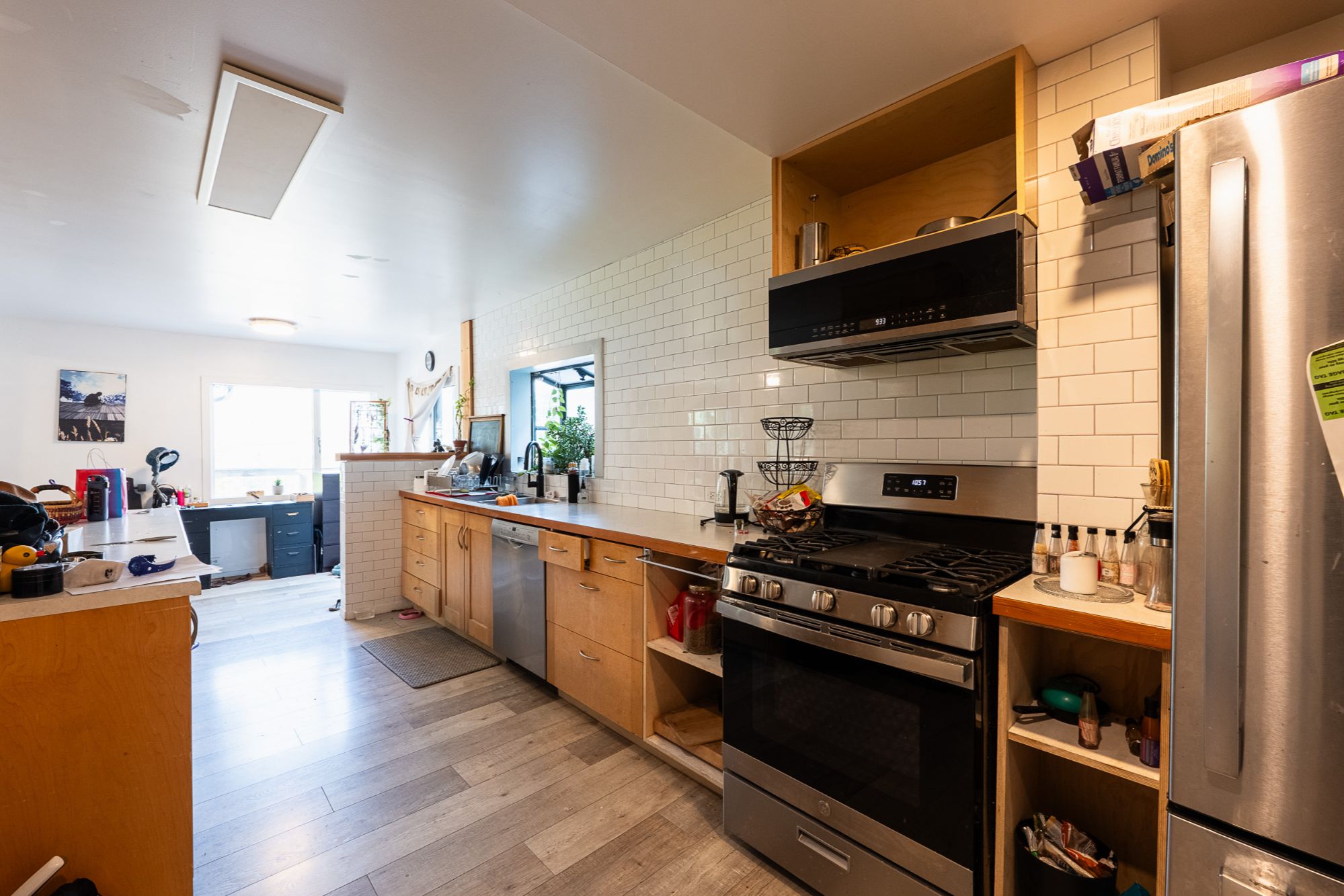 Bright and functional kitchen at 320 Chatham St, Nelson BC, featuring stainless steel appliances, subway tile backsplash, natural wood cabinetry, and open layout with adjacent workspace