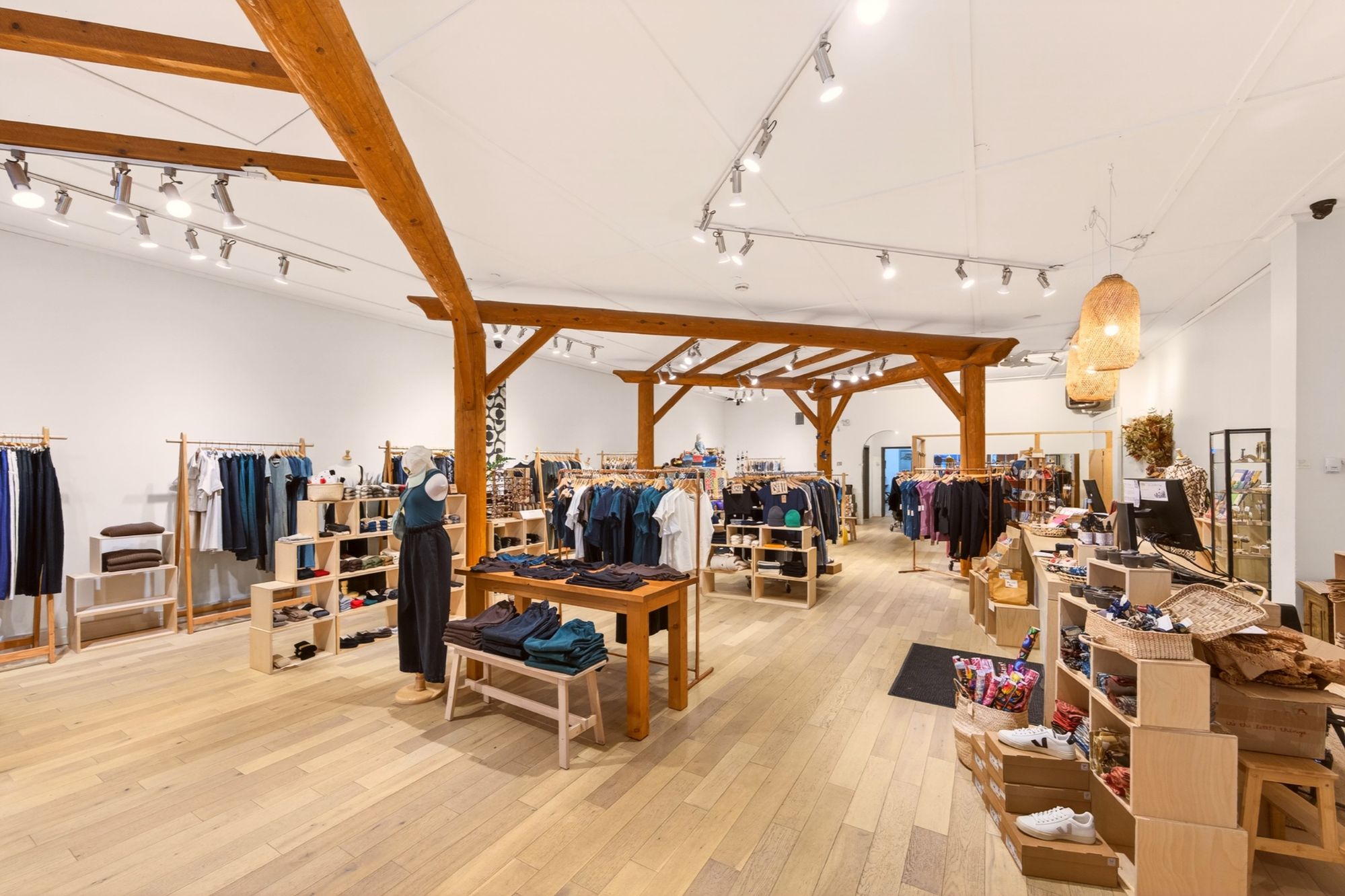 Interior view of fully leased retail space on Baker Street in Downtown Nelson BC featuring 3,600 sq ft open floor plan, high ceilings, exposed timber beams, hardwood flooring, and boutique retail displays.