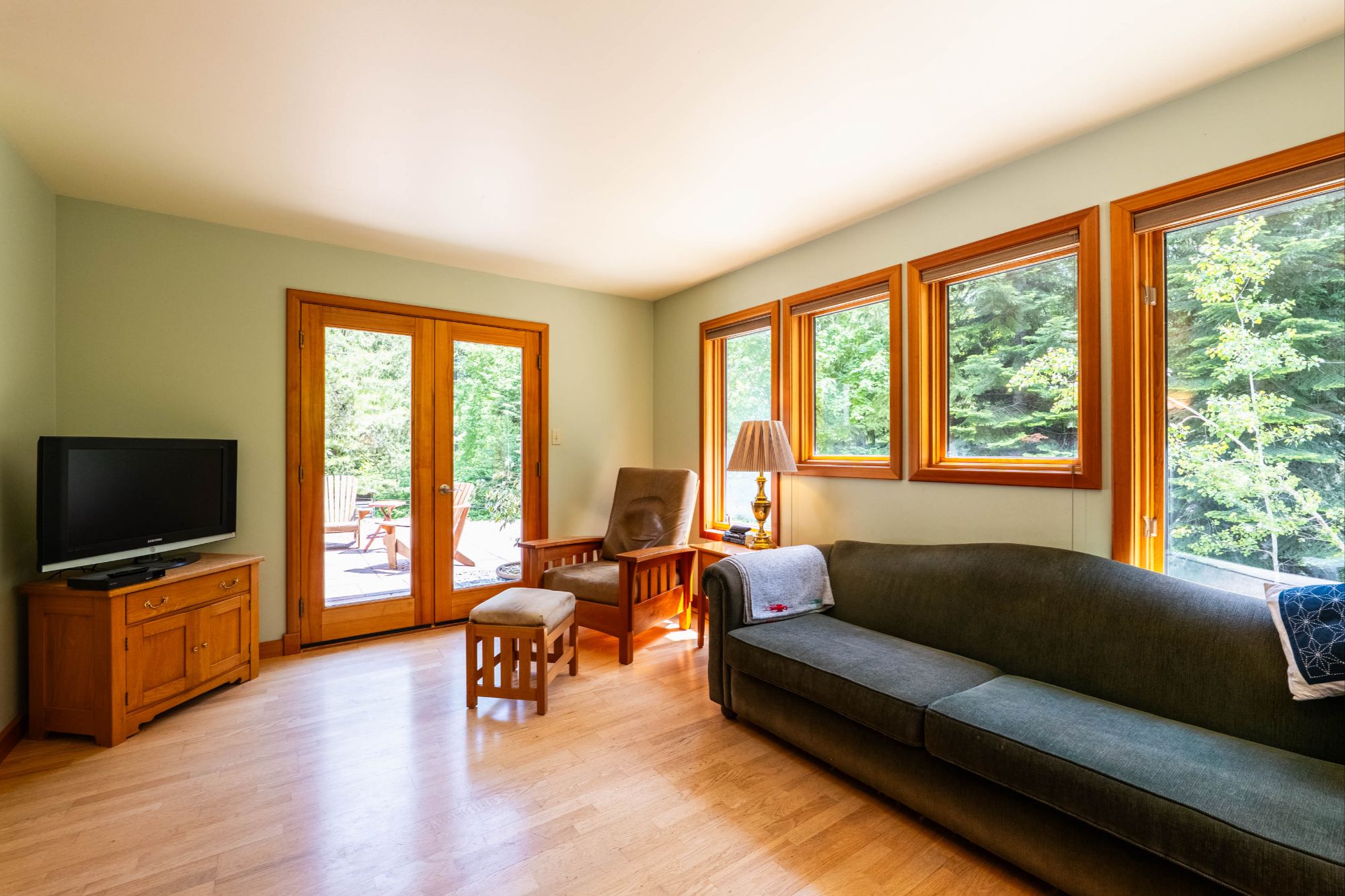 Sun-filled living room with wood finishes, large windows, and patio access in Bonnington Falls BC home near Nelson