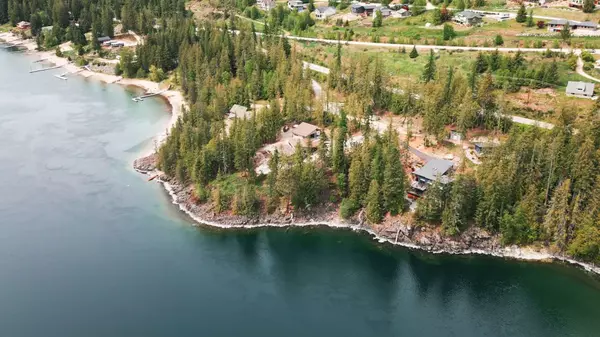 Aerial view of a private waterfront development on Kootenay Lake near Nelson, BC, featuring sandy beaches, forested lots, and upscale homes along the shoreline.
