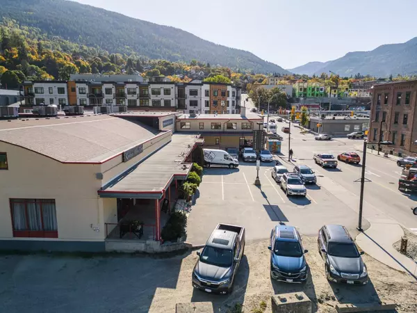 Street-facing view of Gateway Building commercial property in Nelson BC with parking lot, downtown traffic, and mountain backdrop