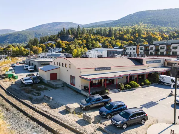Angled rear and side view of Gateway Building commercial real estate in Nelson BC, showing Kootenai Moon Home and surrounding parking and rail line