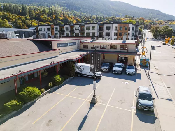 Rear view of Gateway Building commercial property in Nelson BC with parking lot and tenant signage for Torchlight Brewing and Kootenay Optics