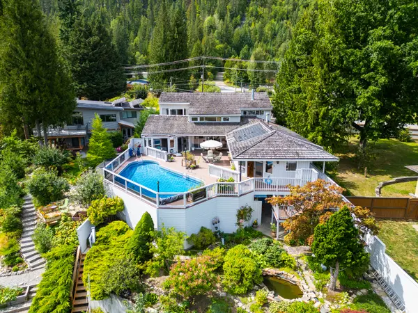 Aerial view of 1896 Hwy 3A, Nelson BC luxury waterfront home featuring pool, patio, landscaped gardens, and koi pond – MLS® 10360967