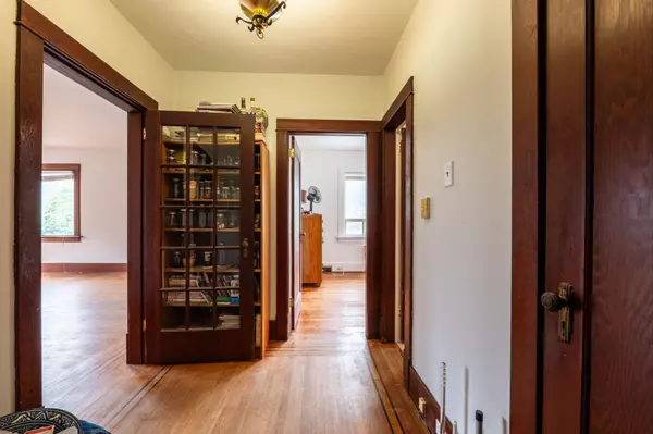 Charming hallway with original hardwood floors, built-in glass cabinet, and vintage wood trim in a multi-unit Nelson BC income property.