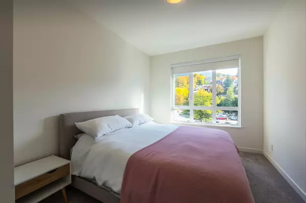 Bright bedroom with large window and scenic views of downtown Nelson and fall foliage in a Nelson Commons condo