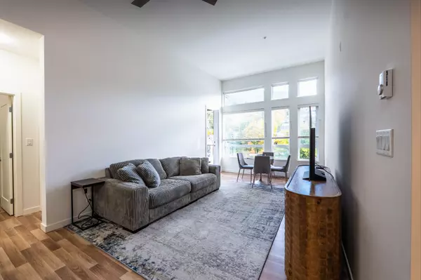 Bright open-concept living and dining area with overheight ceilings and large windows in a top-floor condo at Nelson Commons