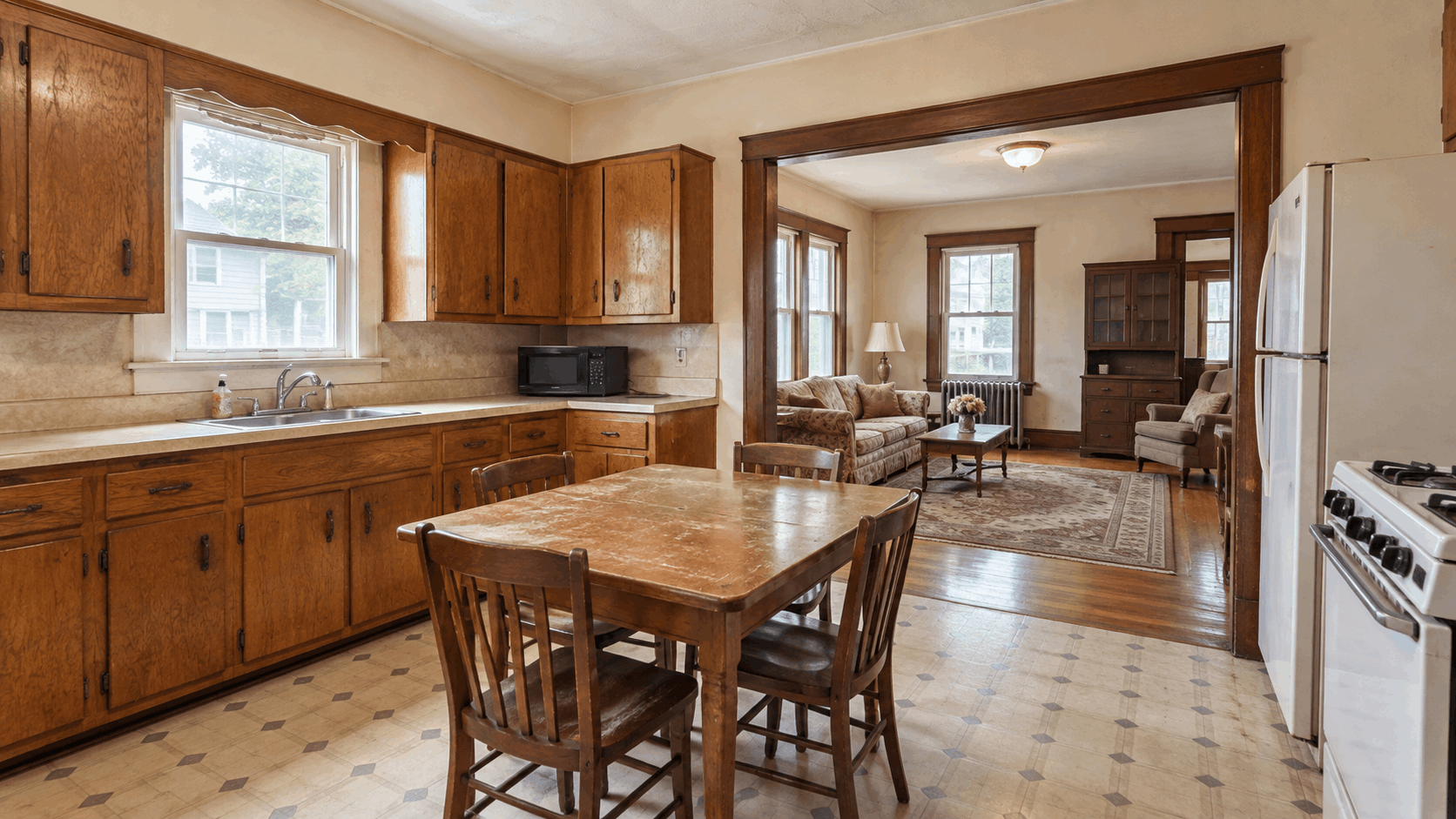 Outdated kitchen in an inherited two-family house in Paterson, NJ, featuring original wood cabinets, aging appliances, worn flooring, and a vintage living room, highlighting a property's condition before an as-is home sale.