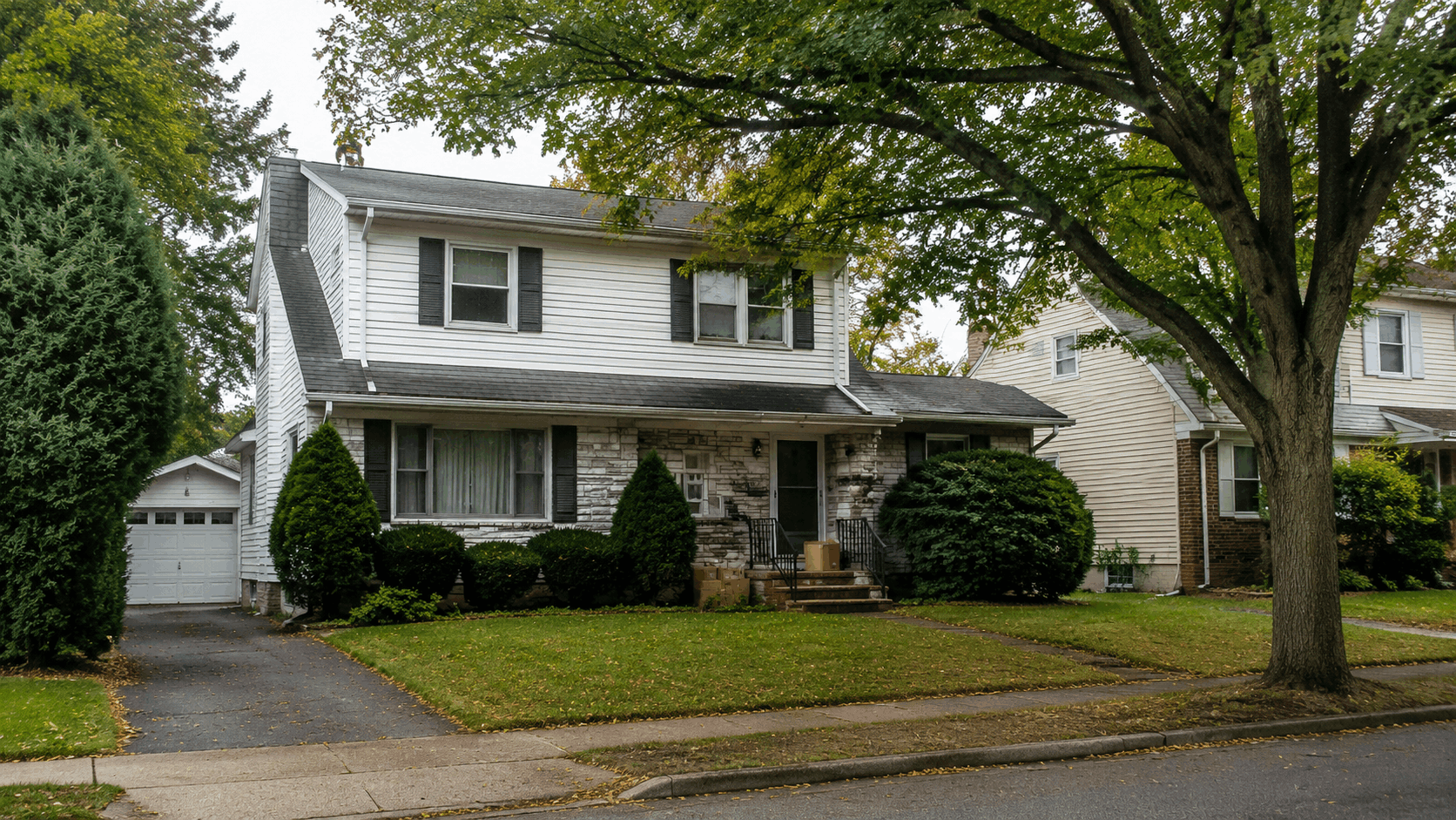 Older North Jersey probate home exterior with mature trees, moving boxes by the front steps, and a well-kept suburban curb appeal.