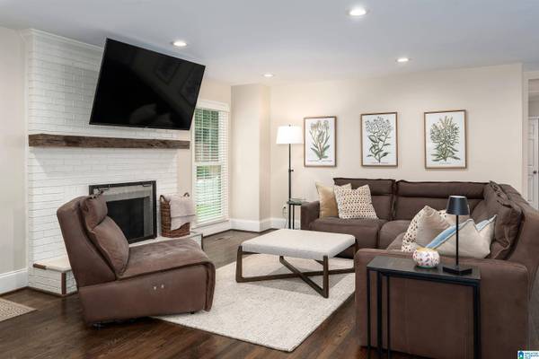 KEYSTONE DRgham, AL 35242, open plan, brick fireplace with mounted TV above, large floor to ceiling single window, sectional sofa and seperate chair, coffee table, smooth ceilings and can lights