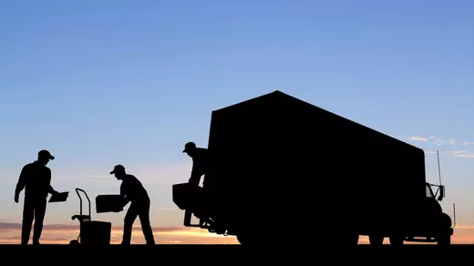 Silhouetted movers unloading a moving truck at sunrise, symbolizing an early start to moving day—professional relocation support featured by Homes With Monika, Arizona real estate guide.