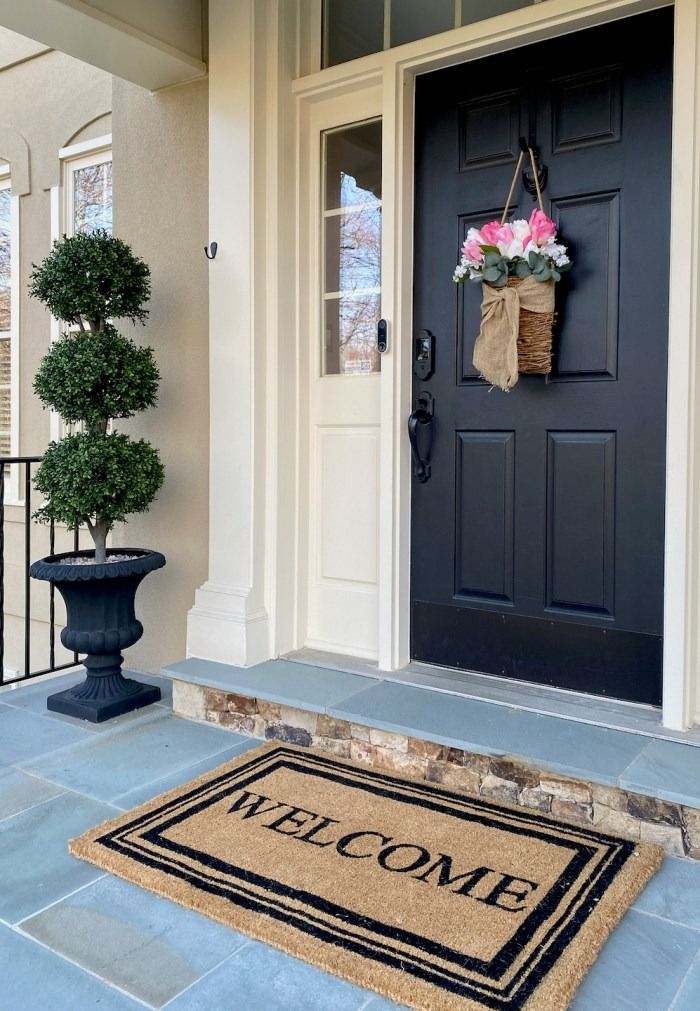 Front porch of a styled home with flowers and a welcome mat