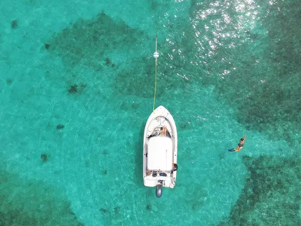 Boat anchored in the middle of the teal ocean in the Florida Keys, with swimmers nearby enjoying the clear, tropical water