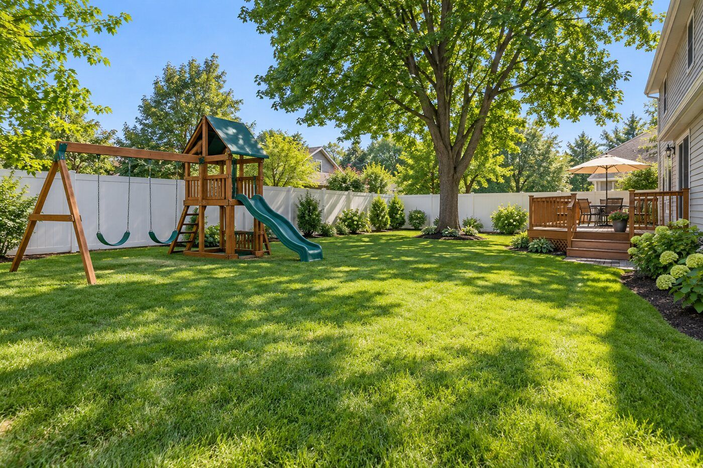 Green fenced backyard with wooden swing set