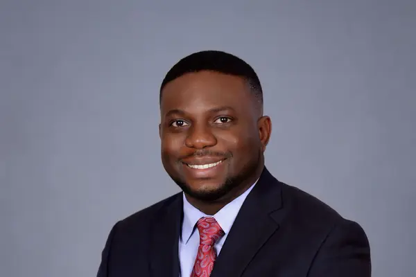 DK Shittu, Edmonton REALTOR® with LPT Realty, smiling in a navy suit and red tie